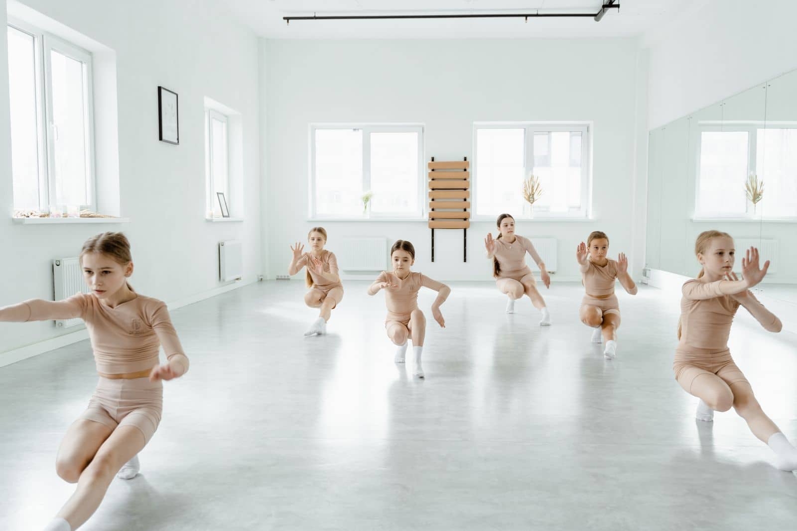 Young girls rehearsing a dance routine in a bright studio