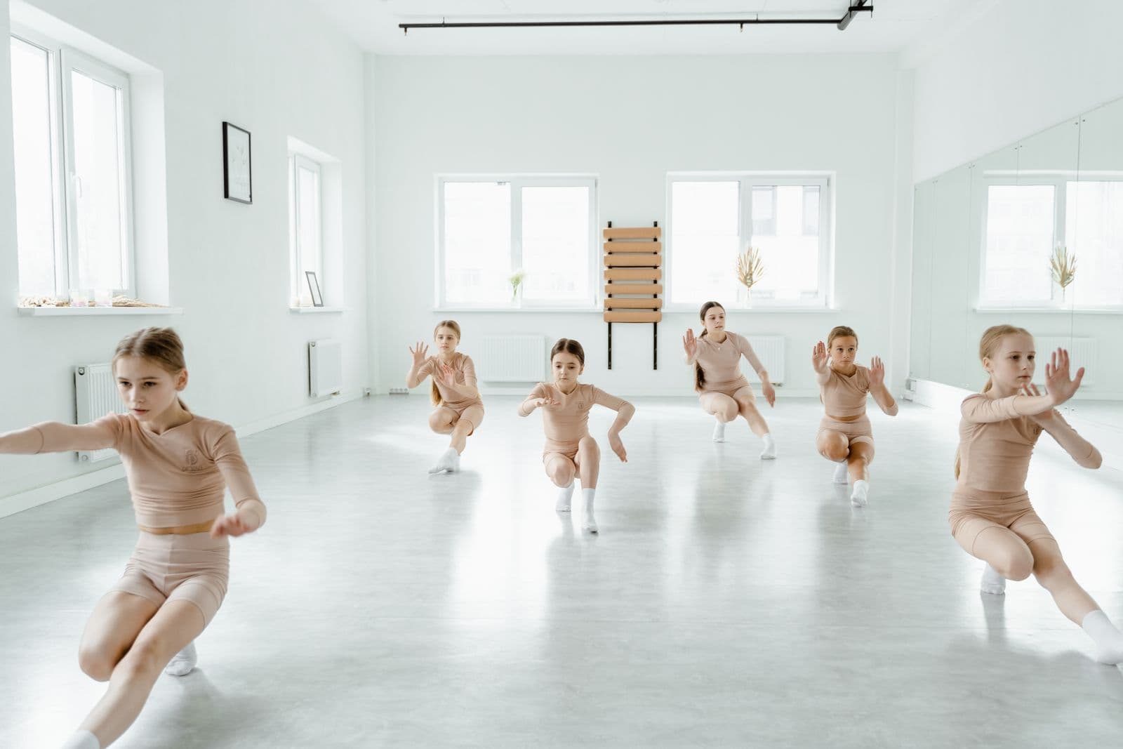 Young girls rehearsing a dance routine together in a bright studio
